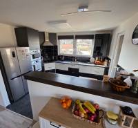 Konyha egy családi házban modern készülékekkel, pulttal és gyümölcsökkel az asztalon.