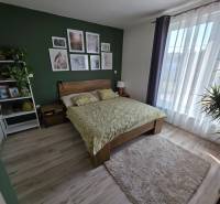 Hálószoba családi házban fa mintázatú padlóval, zöld fallal és virágokkal.