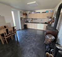 Családi ház konyhája konyhabútorral, étkezőasztallal és tűzhellyel.