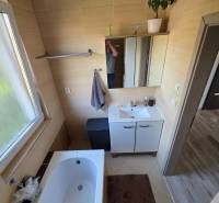 Fürdőszoba családi házban káddal, mosdó alatti szekrénnyel és világos ablakkal.