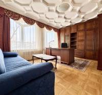 Szoba egy 4 szobás lakásban kényelmes kanapéval, íróasztallal és fa dekorációjú padlóval.