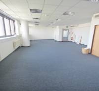 Tágas irodák kék szőnyeggel és ablakokkal a Kutlíkova utcán, Pozsony-Lúky.