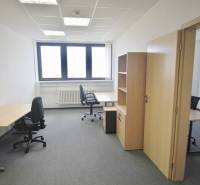 Irodák irodabútorokkal, szürke szőnyeggel és világos fallal, munkára készen.