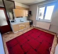 Konyha egy 3 szobás lakásban fa dekoros padlóval és piros szőnyeggel.