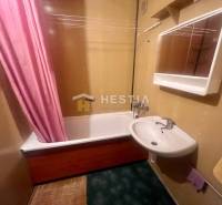 Fürdőszoba mosdóval és káddal egy háromszobás lakásban, a rózsaszín függöny hangsúlyos elemet ad hozzá.