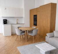 Konyha egy háromszobás lakásban, fa dekor padlóval, szürke szőnyeggel és étkezőasztallal.