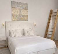 Világos hálószoba ággyal, falon lévő képpel, éjjeliszekrénnyel és fa dekorációjú padlóval.