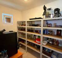 Családi ház kamrája polcokkal, tele készletekkel és konyhai eszközökkel.