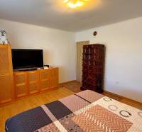 Szoba egy családi házban televízióval, szekrénnyel, cserépkályhával és fa dekorációjú padlóval.