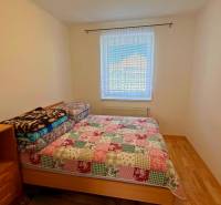 Hálószoba családi házban, ággyal és fa mintázatú padlóval.