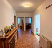 Folyosó a családi házban csempével és fa dekorációs szekrénnyel.