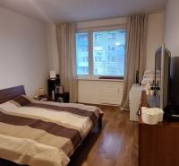 Hálószoba egy 4 szobás lakásban fa mintázatú padlóval és nagy ággyal.