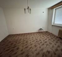 Szoba egy egyszobás lakásban fa dekorációjú padlóval és egyszerű világítással.