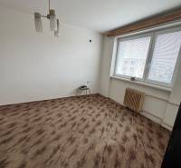 Egy szoba az egyszobás lakásban ablakkal, fehér falakkal és fa dekorációjú padlóval.