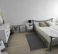 Hálószoba egy kétszobás lakásban világos bútorokkal és fa mintázatú padlóval.