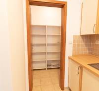 Konyha egy kétszobás lakásban polcokkal és csempével, fa dekoros szekrényekkel.