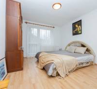 Világos hálószoba családi házban, fa dekoros padlóval és nagy ággyal.