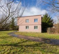 Kétszintes családi ház Tŕstíben, kerttel körülvéve, gyep és fák.