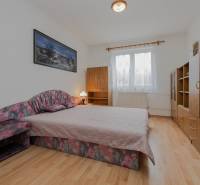 Hálószoba családi házban, fa dekorációjú padlóval, franciaággyal és bútorokkal.