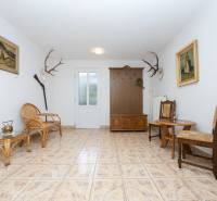 Családi ház belső tere rattan kanapéval, székekkel, díszes agancsokkal és képekkel.