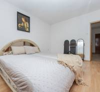 Hálószoba családi házban, fa dekoros padlóval, kényelmes ággyal és képpel a falon.