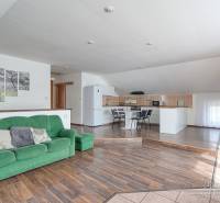 Családi ház belső tere kanapéval, konyhasarokkal és fa dekorációjú padlóval.