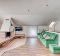 Nappali családi házban kandallóval, zöld kanapéval és fa dekoros padlóval.