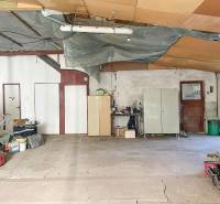 Családi ház belső tere tágas helyiséggel, elrakott dolgokkal és cementpadlóval.