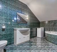 Fürdőszoba családi házban káddal, zöld csempékkel és fehér bútorokkal.