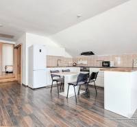 Konyha étkezőasztallal és háztartási gépekkel egy családi házban, fa dekorációjú padlóval.