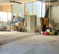 Családi ház garázsa tele szerszámokkal és gépekkel, különféle felszerelésekkel a polcokon.