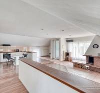 Nappali kandallóval és konyhai résszel, fa dekoros padlóval, világos szoba.