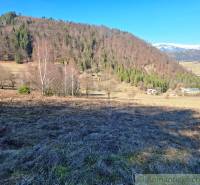 Kilátás a lakóövezeti telkekre Hroncban, háttérben erdőkkel és hegyekkel.