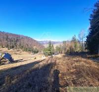 Táj Hronec községben, mezőgazdasági és erdőterületek hegyekre és házakra néző kilátással.