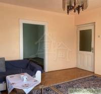 Nappali egy családi házban, fa dekor padlóval, kanapéval és szőnyeggel.