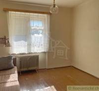 Szoba egy családi házban kanapéval, ablakkal és fa dekorációjú padlóval.