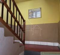 Lépcsőház fa korláttal egy családi házban, sárga falakkal és egy képpel.