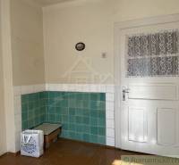 Családi ház belső tere fehér ajtókkal és zöld-fehér csempékkel a falakon.