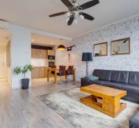 Nappali egy háromszobás lakásban, fa dekoros padlóval és bőr kanapéval.