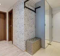 Folyosó fa dekor padlóval, fehér fallal és fényes paddal egy háromszobás lakásban.