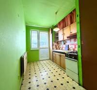 Konyha egy kétszobás lakásban, konyhabútorral, zöld falakkal és fekete-fehér padlóval.