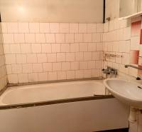 Fürdőszoba egy kétszobás lakásban káddal, mosdóval és régebbi fali csempékkel.