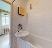 Fürdőszoba káddal és fehér csempékkel egy kétszobás lakásban.