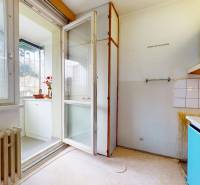 Konyha fehér szekrényekkel, világítással és kilátással az erkélyre egy kétszobás lakásban.