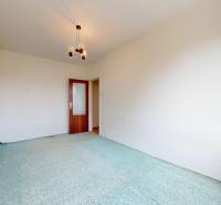 Szoba egy kétszobás lakásban szőnyeggel és mintás függönnyel.