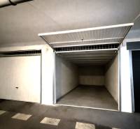 Nyitott garázs üres belső térrel és fehér falakkal.