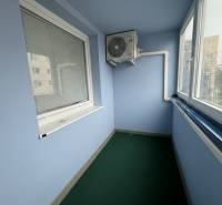 Üvegezett lodzsa klímaberendezéssel egy 2 szobás lakásban, redőnyökkel és zöld szőnyeggel felszerelve.