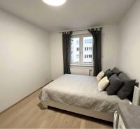 Hálószoba ággyal és fa dekorációjú padlóval egy kétszobás lakásban.