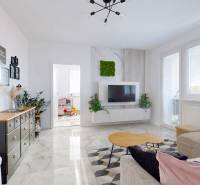 Nappali egy háromszobás lakásban dekoratív asztallal és falra szerelt televízióval.