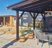 Kültér Újfaluban vendéglátóhelyiségekkel, terasszal és játszótérrel.